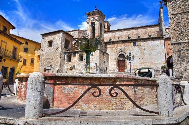 10 Città turistiche in Umbria da visitare, tra chiese romaniche 11 Fontana storica in piazza nel centro storico di un paese italiano, con edifici antichi e cielo azzurro, atmosfera estiva, patrimonio culturale, tipico scenario di città italiana, architettura tradizionale.