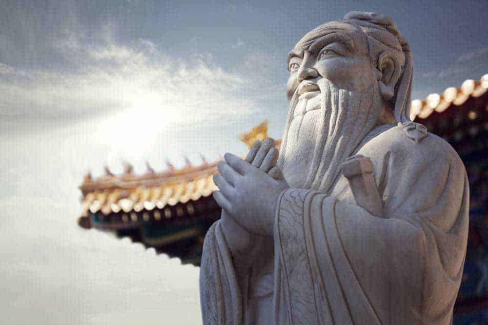 Forza interiore: Statua di un antico dio cinese in pietra, simbolo di saggezza e spiritualità, con un tempio tradizionale sullo sfondo, al tramonto, in stile artistico e culturale orientale.