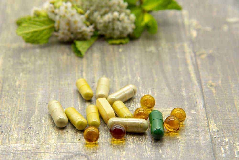 Integratori vitaminici e minerali con capsule e perle su superficie in legno, concetto di salute naturale e benessere.