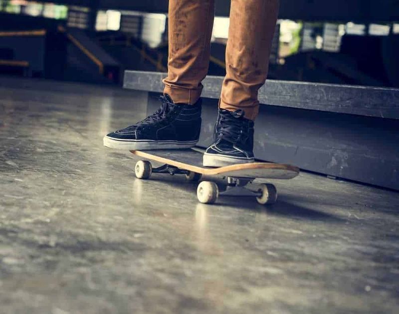 Calzature uomo estive 2023, tra scarpe sportive, perfette per la moda 4 Skateboarder in scarpe da ginnastica nere in azione in skate park, mostra di abilità e stile con tavola da skateboard, ambiente urbano dedicato allo sport e alla cultura skate.