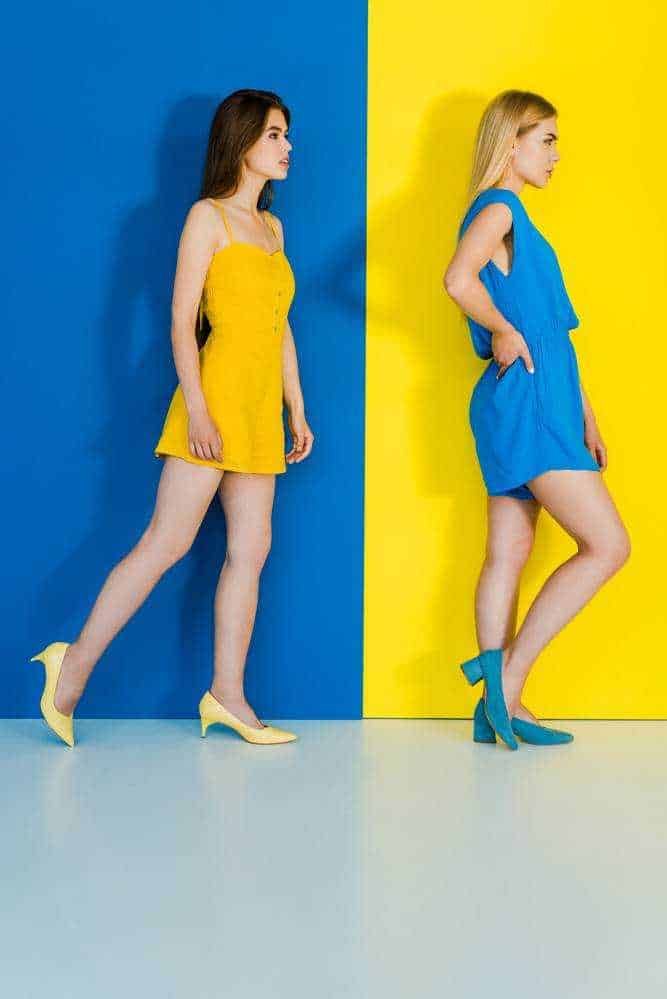 Vestito giallo e blu abbinato, donna alta e donna bassa in posa artistica contro pareti colorate, moda e stile femminile, fotografia di moda moderna, ispirazione fashion, colori vivaci e outfit femminili.