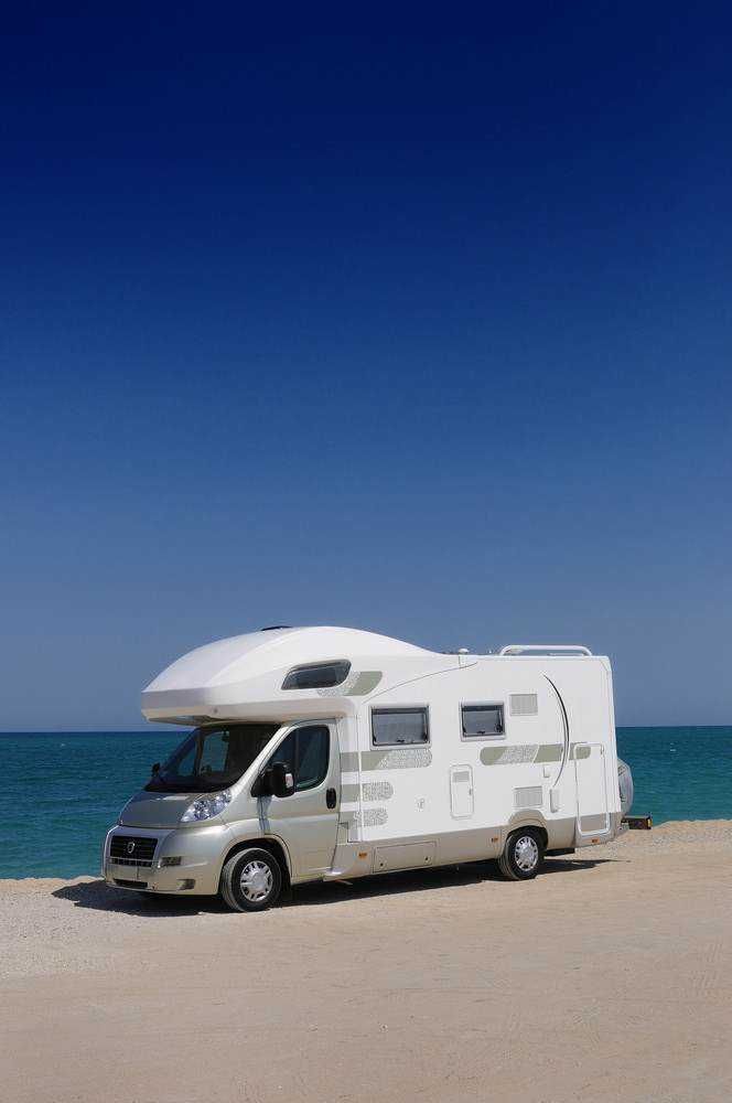 Camping van sul mare con vista spiaggia e cielo sereno, ideale per vacanze estive e avventure outdoor.