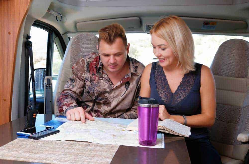 Viaggio in camper: coppia che pianifica il percorso con mappa e smartphone, destinazione all'aperto, stile di vita libero e avventuroso, tecnologia e natura, itinerario di viaggio.