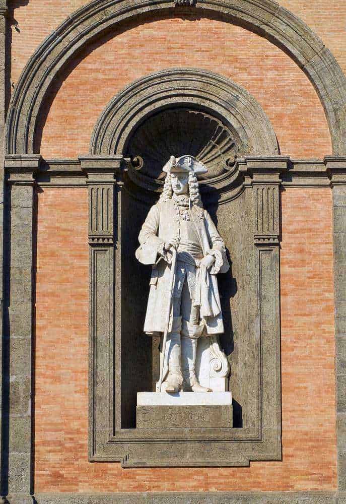 Grande edificio storico con arcate e grandi vetrate, stile architettonico classico, situato in una piazza pubblica, suggestiva illuminazione naturale, facciata ornata di dettagli eleganti, rappresenta patrimonio culturale e architettonico.