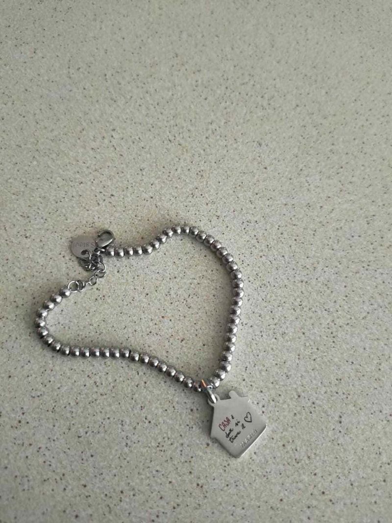 Come Riconoscere l'Argento Vero: 10 Tipi, Punzoni e 7 Test Infallibili 3 Bracciale con charm personalizzato in acciaio inox, elegante e adatto come regalo speciale, perfetto per occasioni romantiche o anniversari, sul tavolo di vetro.