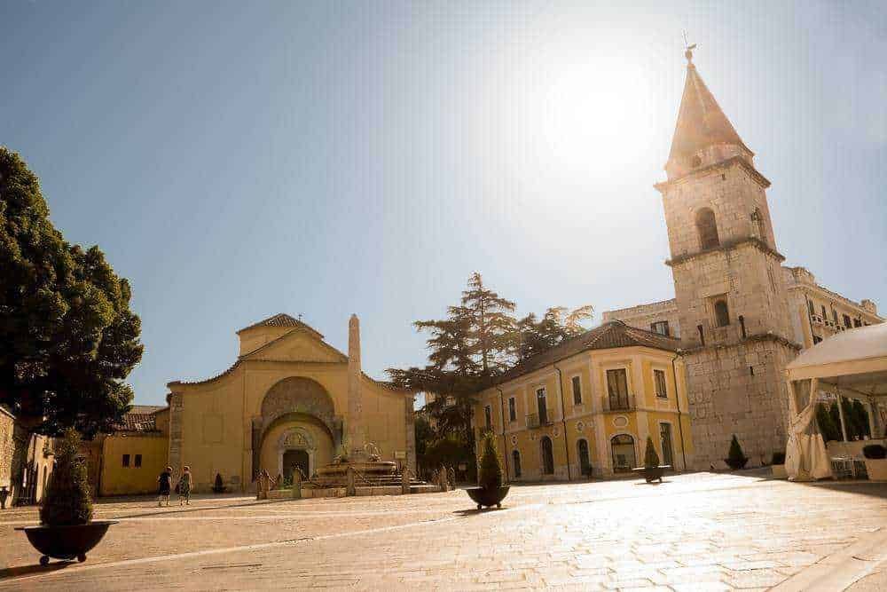 Antica piazza con torre storica e chiesa in stile medievale a Ragusa Ibla, Sicilia, al tramonto, con luce calda e atmosfera suggestiva.