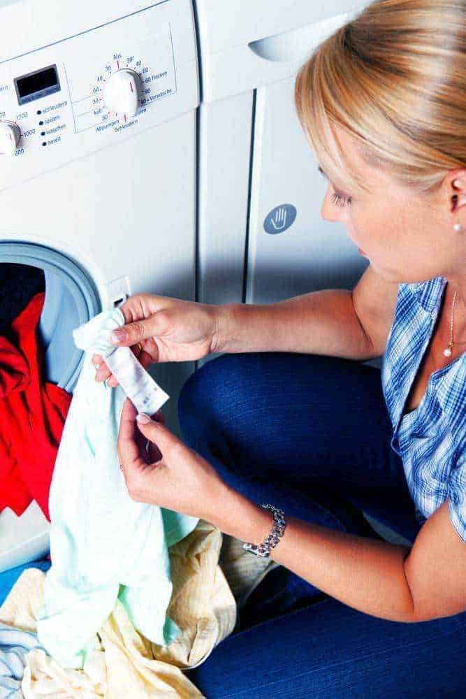 Lavatrice che carica vestiti, donna che inserisce detersivo, igiene domestica, cura del bucato, silenziosa routine di lavanderia domestica.