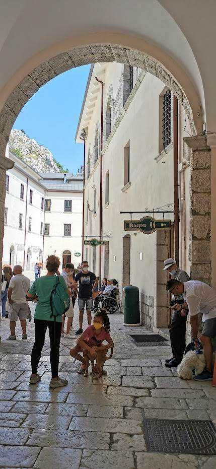 Passeggiata nel centro storico di Napoli sotto un arco, con turisti e residenti, negozi tipici e un'atmosfera vivace, in una giornata soleggiata.