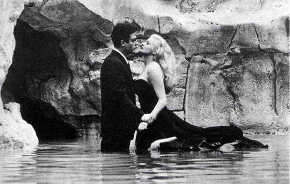 Lui e lei si baciano in acqua di un ruscello ciottoloso, creare un'atmosfera romantica e suggestiva, ideale per temi d'amore e momenti speciali di coppia.