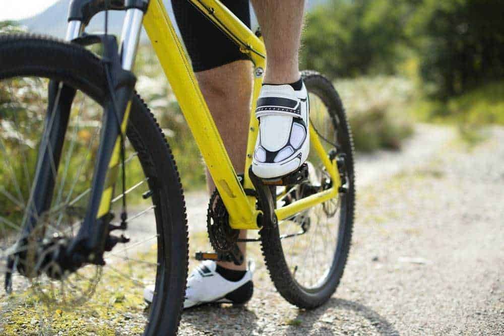 Ciclista su mountain bike in natura, dettagli sulla pedalata e il percorso outdoor, ideali per appassionati di sport e avventure all'aria aperta.