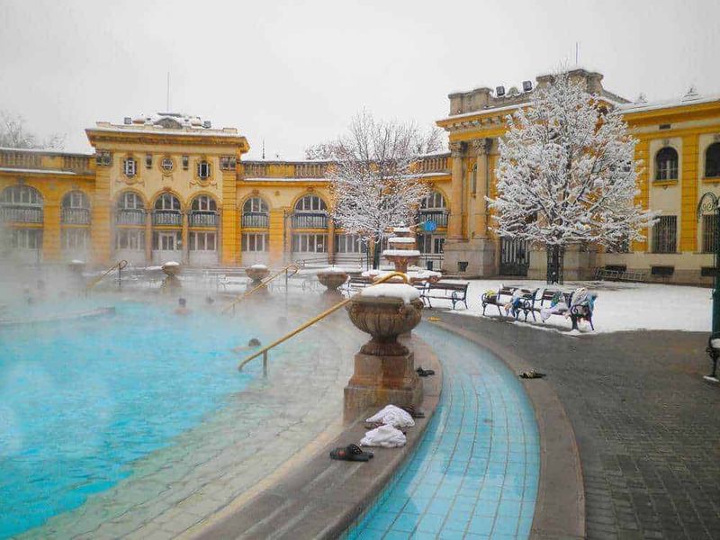 Bagno termale con neve e edificio storico in stile liberty, in una giornata invernale.