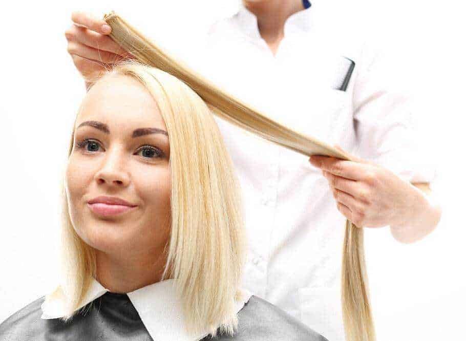 Extension per capelli: Capelli biondi lisci, taglio bob, parrucchiere professionista che acconcia capelli con attenzione e cura.