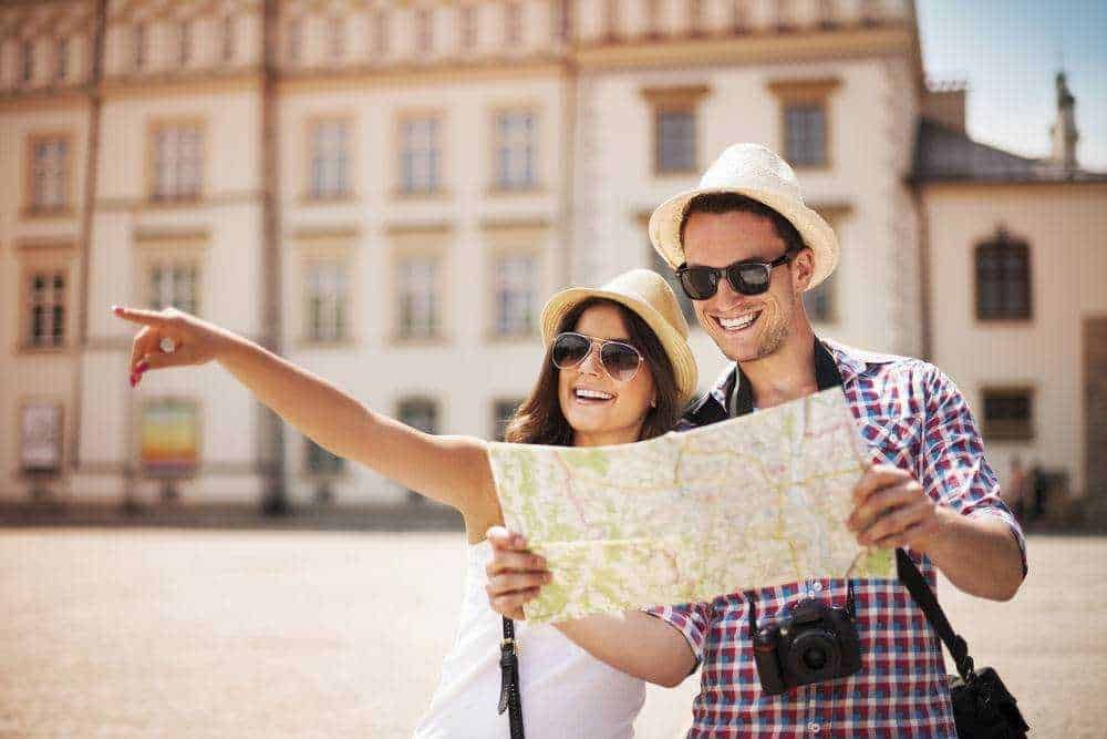 Destinazioni incantevoli per viaggi indimenticabili. Viaggiatori felici che pianificano un itinerario turistico con mappa in centro città.