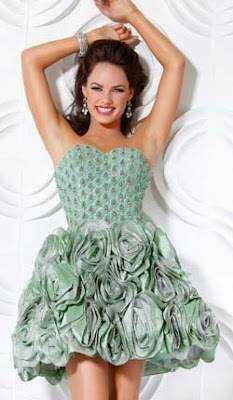 Una giovane donna sorridente indossa un abito elegante verde con dettagli floreali, che mette in evidenza stile e raffinatezza, ideale per occasioni speciali.