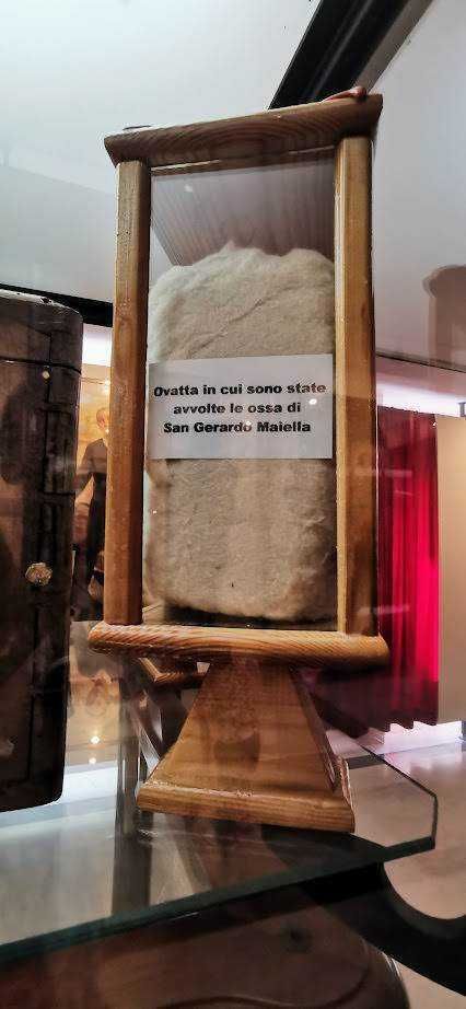 Ossa di San Gerardo Maiella esposte in un frammento di ossario, simbolo di fede e devozione religiosa, conservate in un’apposita cornice di legno, in un’esposizione museale di reperti sacri.