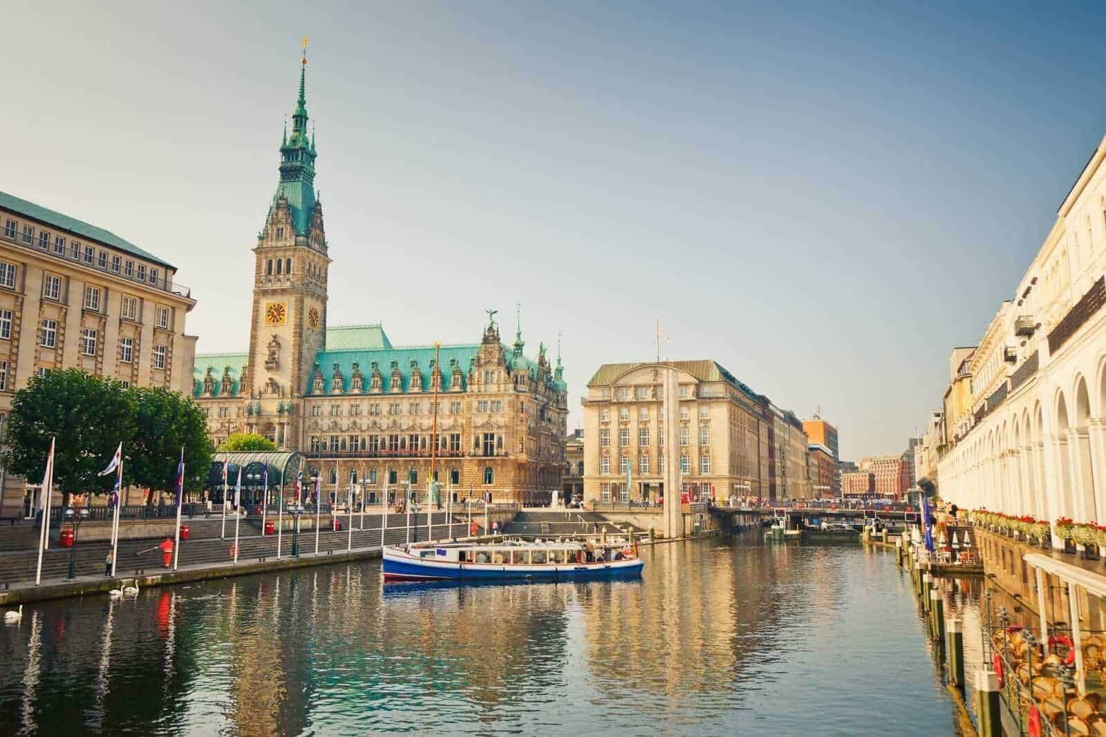 Palazzo del Municipio di Hamburgo con il suo campanile storico, vista sul porto e il fiume Alster, in una giornata di sole senza nuvole, tra edifici storici e moderni.
