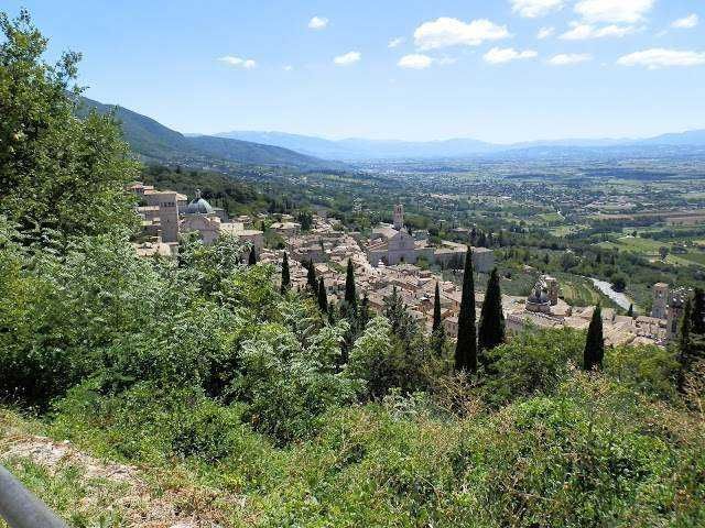 Vista panoramica di un antico cimitero in collina con cipressi e paesaggio rurale circostante