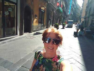 Immagine di una donna sorridente con occhiali da sole in via Toledo a Napoli, Italia, durante una passeggiata turistica.