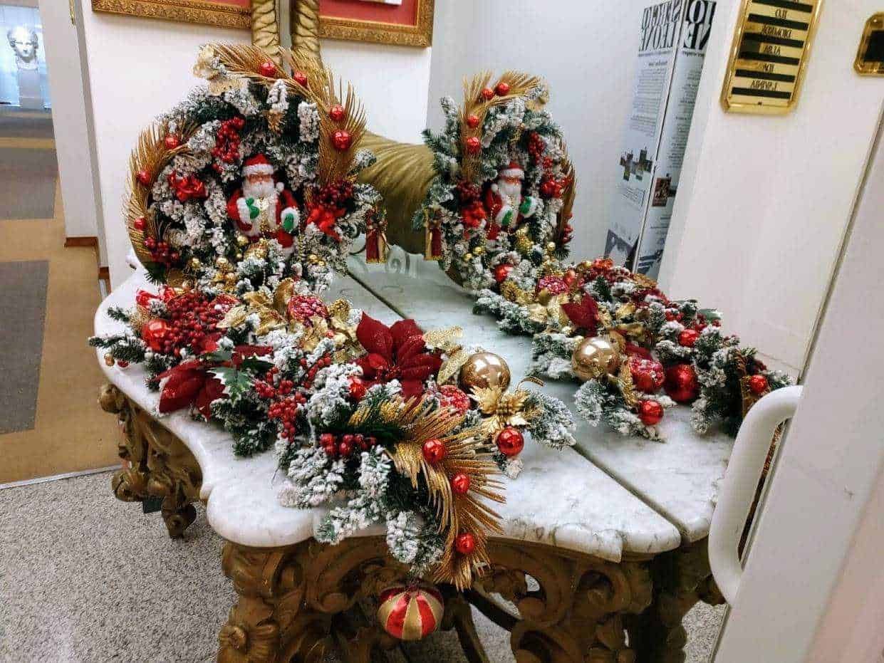 Addobbi natalizi floreali con pino innevato, palline rosse e decorazioni dorate sul tavolo in marmo, ideale per decorazioni festive di Natale.