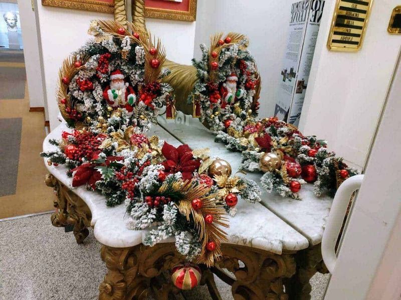 7 piante di Natale da regalare 6 Addobbi natalizi floreali con pino innevato, palline rosse e decorazioni dorate sul tavolo in marmo, ideale per decorazioni festive di Natale.