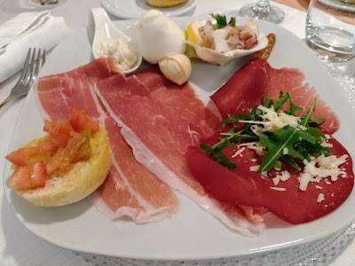 Immagine di un antipasto a base di prosciutto crudo e scaglie di formaggio