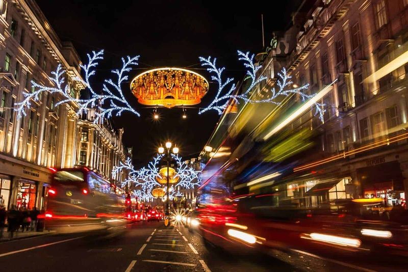 Eventi natalizi in Europa da non perdere 7 Vetrine di negozi decorate con luci natalizie sulla via principale di notte durante le festività festive.