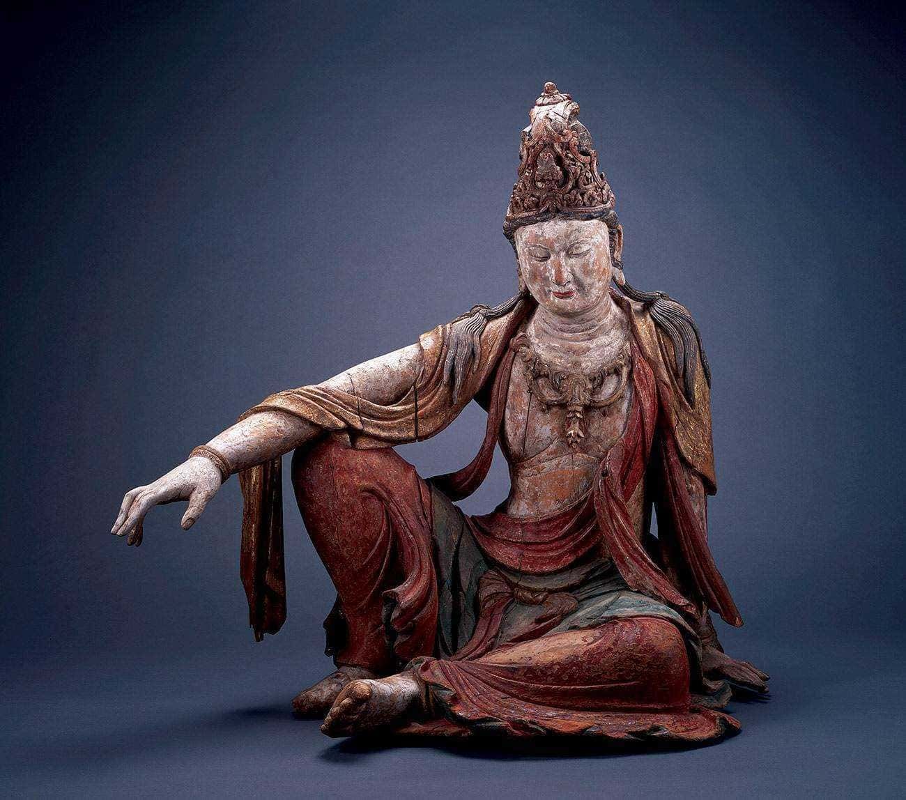 Antica statua in legno colorato di una dea buddista giapponese, rappresentata seduta con un'espressione serene, ornata di dettagli elaborati e simbolici, perfetta per collezionisti e appassionati di arte asiatica.