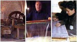 Museo della carta e della filigrana di fabriano: Antico mulino a vento e ingranaggi in legno, simbolo di tradizione e artigianato italiano, con un vecchio uomo che lavora davanti a un fiume in cascata, e un bambino che scrive su un quaderno a scuola.