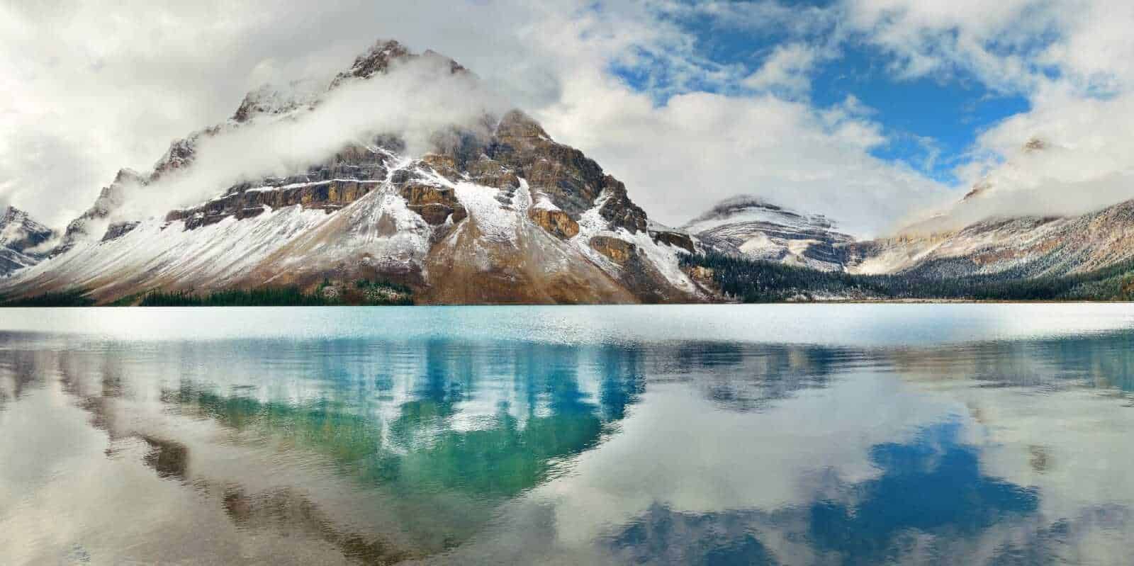 Montagne innevate e riflessi di un lago cristallino circondato da paesaggi naturali spettacolari.