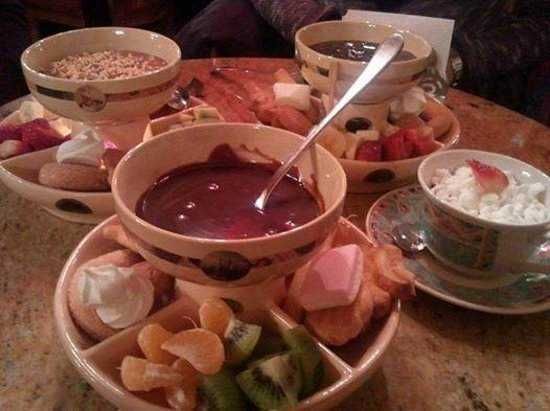 Cioccolaterie a parigi: Delizie di cioccolato e frutta fresca in ciotole di ceramica, perfette per una colazione o dessert goloso, accompagnate da panna montata e biscotti. Locale accogliente per momenti conviviali.