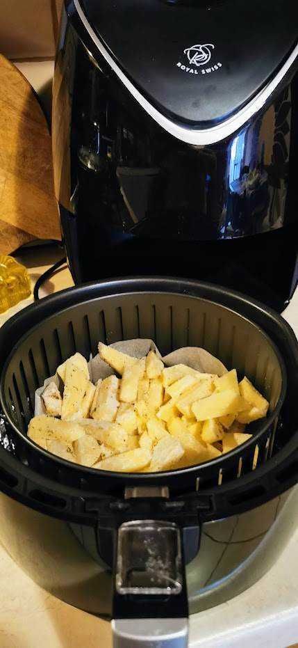 Fette di formaggio nel cestello di una friggitrice ad aria, pronta per essere cotte, con sfondo di un'apparecchiatura da cucina moderna.