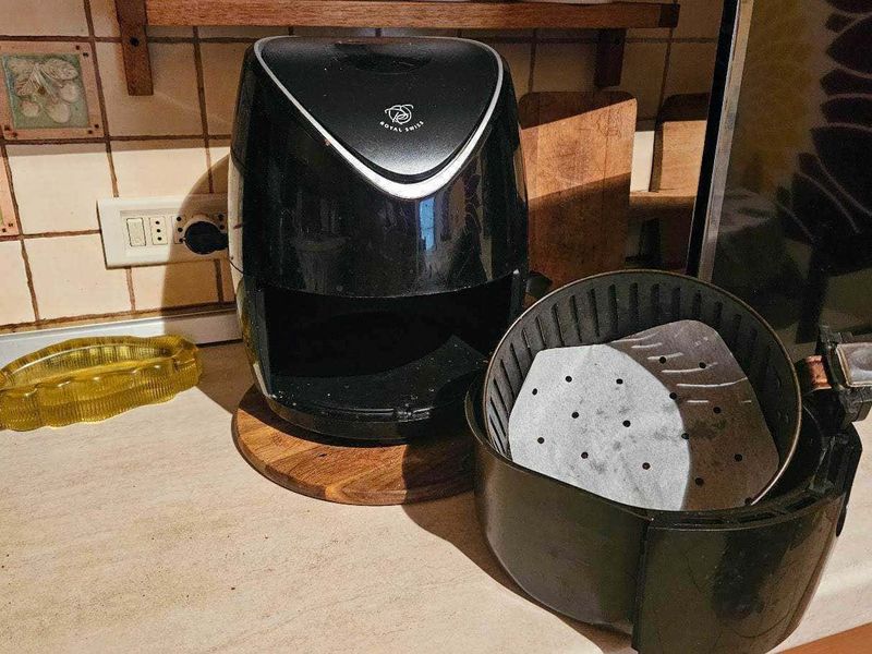 Perchè usare la friggitrice ad aria? pro e contro 6 Frittaia ad aria, con l’interno rivestito di carta, posizione di riposo sul piano cucina in stile rustico.