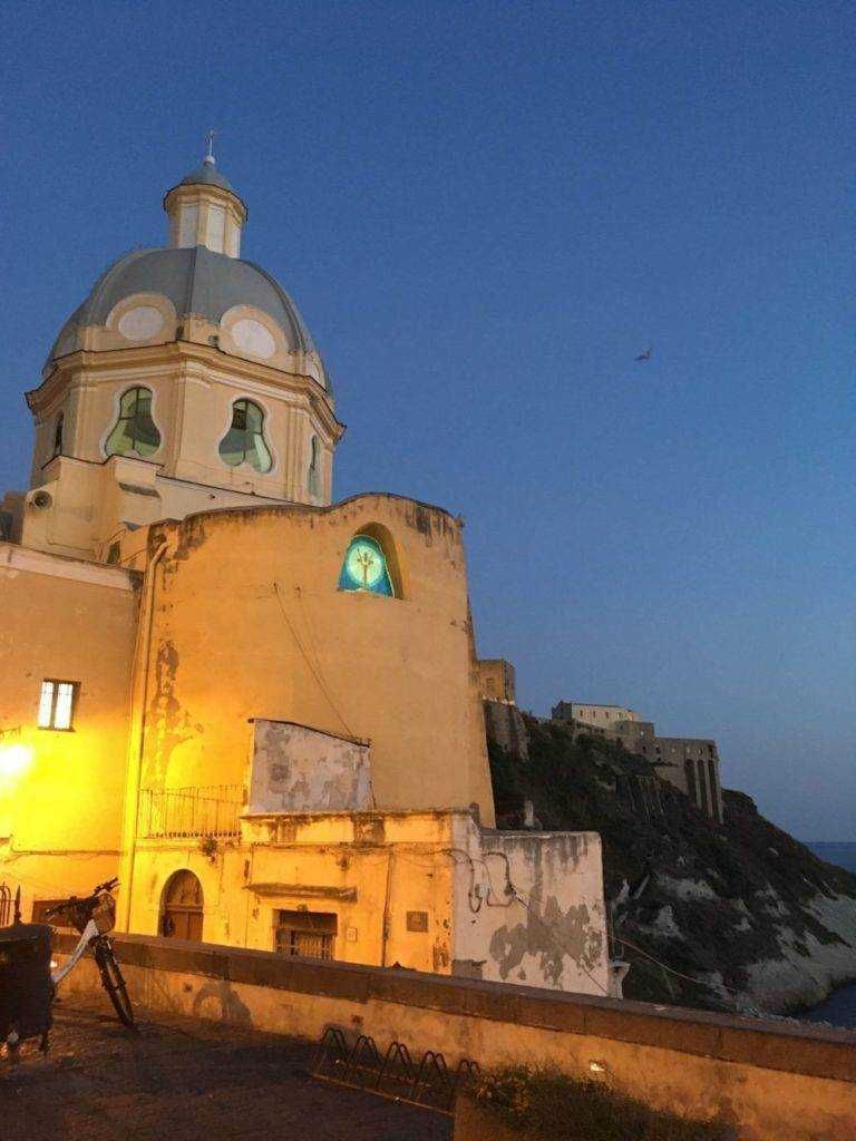 Vecchia chiesa sulla scogliera di Positano con illuminazione serale, vista suggestiva del mare e del cielo al tramonto, perfetta per appassionati di viaggio e fotografia di luoghi iconici italiani.