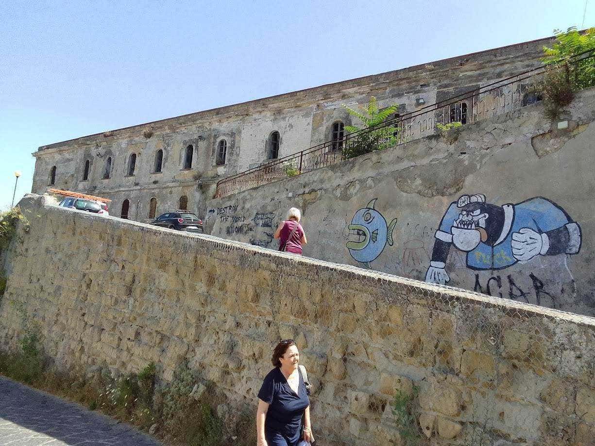 Colorata street art graffiti su muro di pietra antico con persone che passeggiano, scenario urbano storico e moderno, wall art creativa, ambiente cittadino, arte urbana.