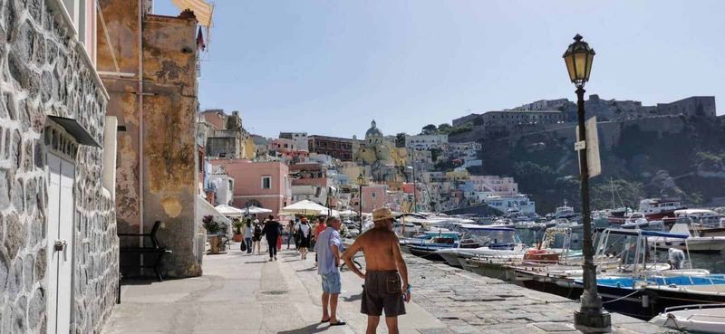 Procida: isola dei pescatori e cultura 9 Barca di molo con yacht e case colorate sullo sfondo nel Porto di Positano, Italia, durante una giornata soleggiata, con turisti che passeggiano lungo il lungomare.