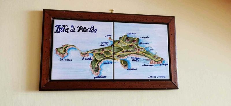 Procida: isola dei pescatori e cultura 2 Colorful hand-painted map of the island of Procida, Italy, showing beaches, landmarks, and local areas, framed on a wall. Ideal for travel, tourism, and Italian island exploration content.