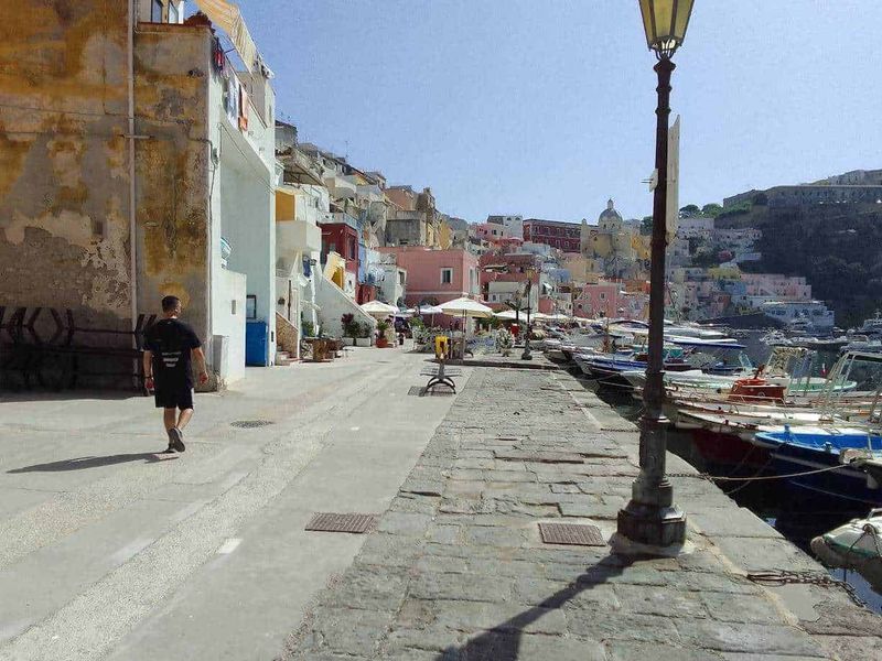Procida: isola dei pescatori e cultura 11 Colorato porto di Sicilia con case color pastello e barche nel mare, atmosfera di vacanza, turismo e relax.