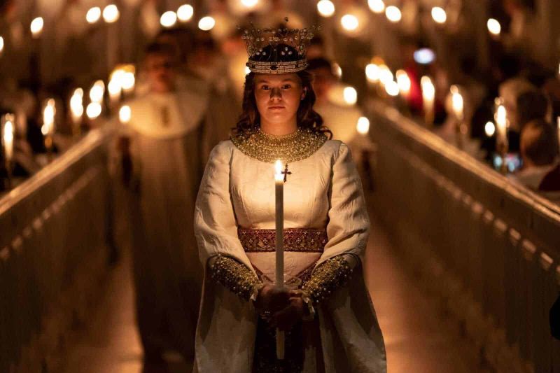 Santa Lucia martire di Siracusa: Storia, Simboli e Tradizioni (2026) 3 Candela liturgica e donna vestita in abito tradizionale, durante una cerimonia religiosa notturna in chiesa, con molte candele accese, atmosfera solenne e spirituale.