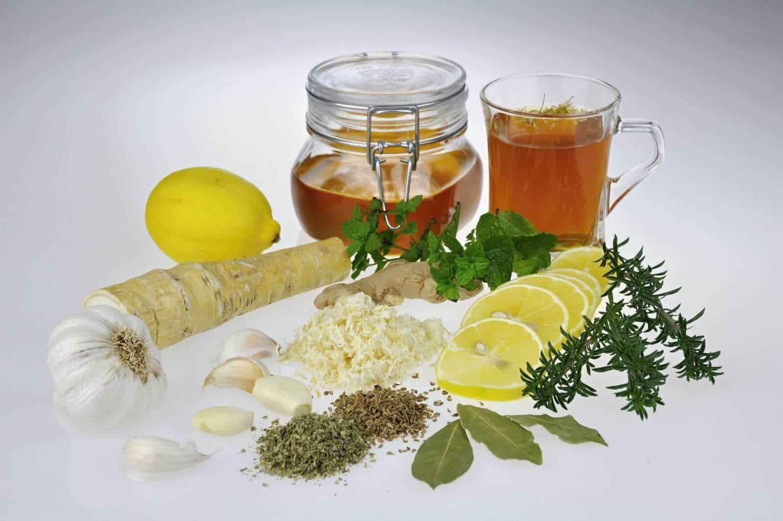 Erbe espettoranti per la tosse: Aromi di zenzero, limone e erbe fresche per infusi e tisane salutari, con miele, aglio e spezie come timo e rosmarino, ideali per benessere naturale e cucina salutare.