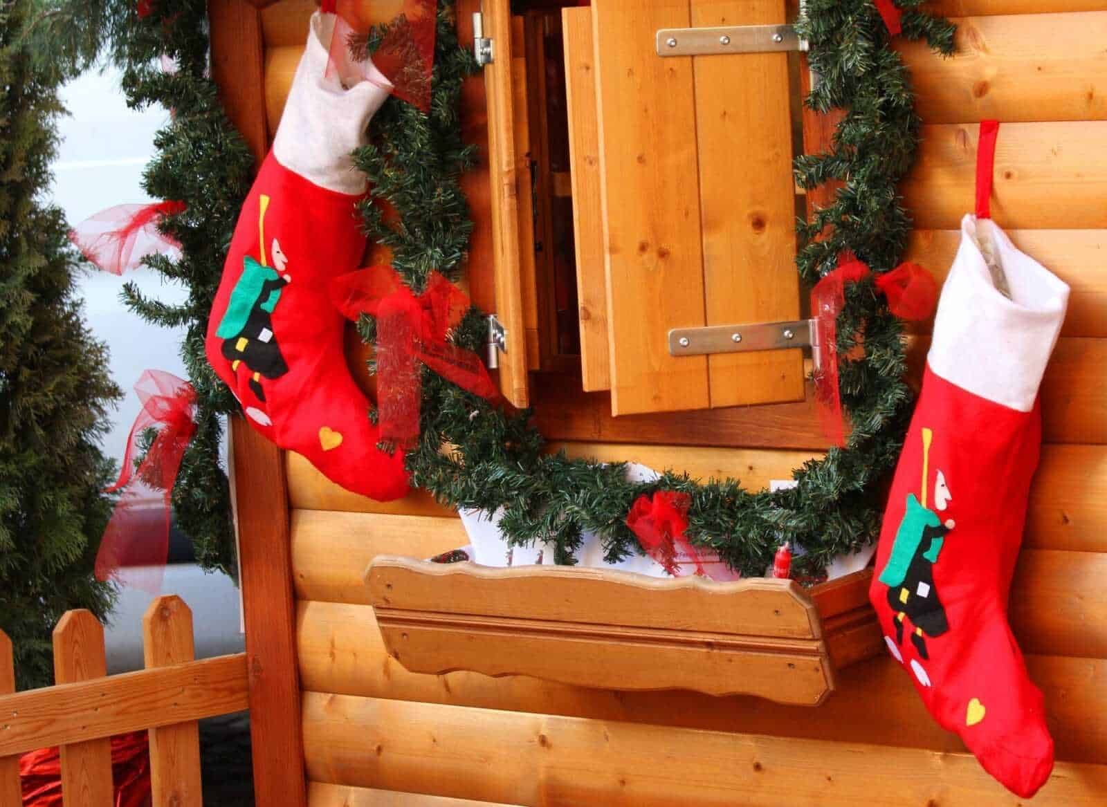 Fiocchi di neve e ghirlande natalizie decorate sulla finestra di legno delle case di montagna, atmosfera calda di Natale, decorazioni festive, foto di decorazioni natalizie, appunti sul blog, atmosfera accogliente, ambiente di festa, atmosfera natalizia.