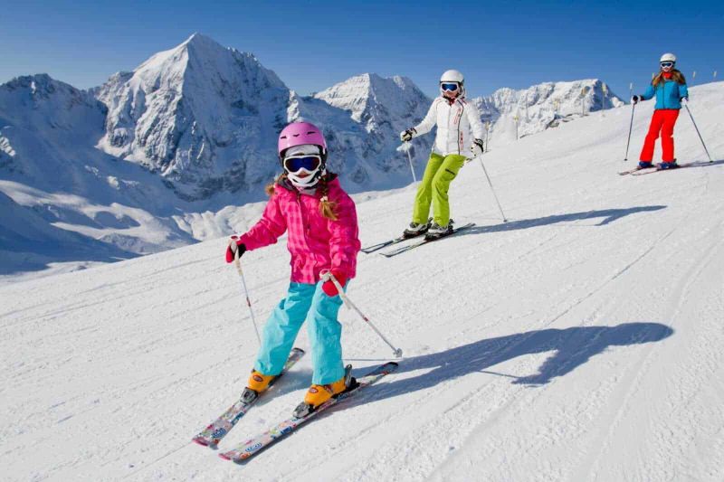Tradizioni natalizie uniche in montagna 2 Neve e sport in montagna con bambini che sciano sulle Dolomiti, paesaggi innevati, attività invernali per famiglie.