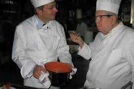 Fiera del Riso a Isola della Scala: Guida, Storia e Cosa Mangiare (2026) 6 Titolare di ristorante in cucina con chef che tiene la mano, scena professionale, chef in abbigliamento da cucina, atmosfera di lavoro gastronomico, cucina italiana, preparazione piatti.