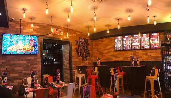 Trattoria la Cueva mangiare argentino a Napoli 2 Trattoria la cueva a napoli: Tavoli in un bar o ristorante con decor moderno, luci calde e menu digitali, atmosfera invitante e accogliente, ideale per incontri sociali e momenti di relax con cibo e bevande.