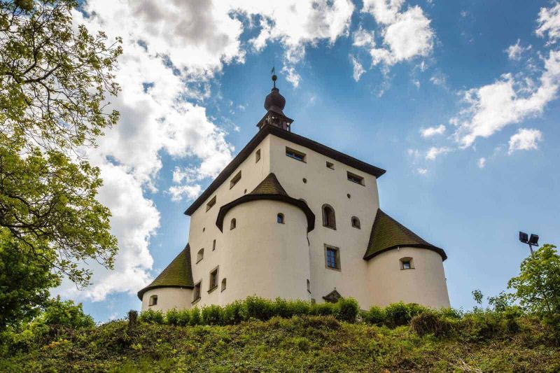 Luoghi delle riprese del romanzo horror Dracula, serie TV Netflix, in Slovacchia 2 Romanzo horror Dracula: Dracula netflix: Castello medievale in collina con cielo azzurro e nuvole bianche, architettura storica, panorama delle Torri in Austria, attrazioni turistiche, struttura immersa nel verde, edificio storico, viaggio culturale, paesaggio pittoresco, monumento storico, escursioni in montagna, destinazioni Europee, patrimonio UNESCO, avventure e storia.