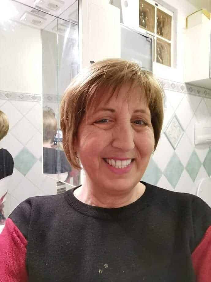 Smile di donna in cucina, ritratto informale di una donna sorridente in un ambiente domestico con piastrelle e cucina moderna sullo sfondo.