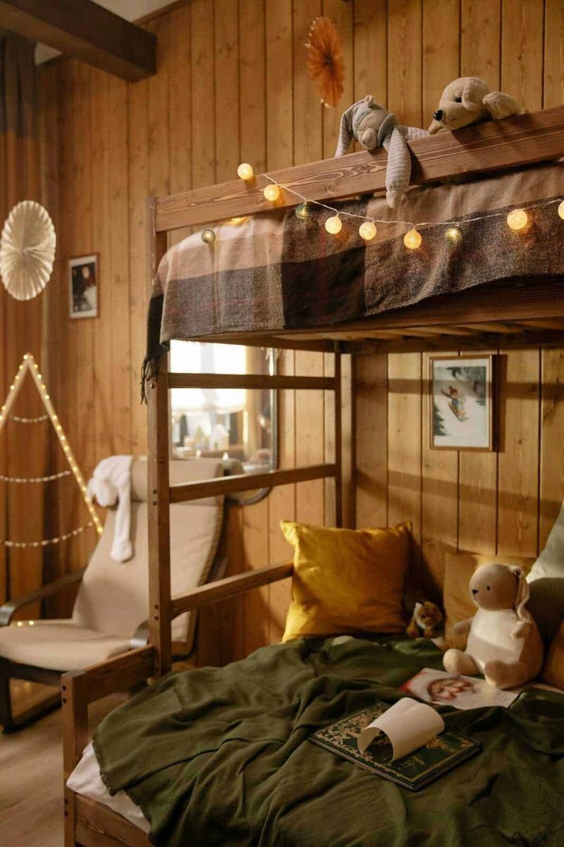 Letto singolo con cassetti o letto a castello legno massello? 4 Letto a soppalco in stile rustico decorato con luci di Natale, peluche e tende a quadri, ambientazione accogliente e calda in un chalet di legno, atmosfera di casa e comfort per bambini e adulti.