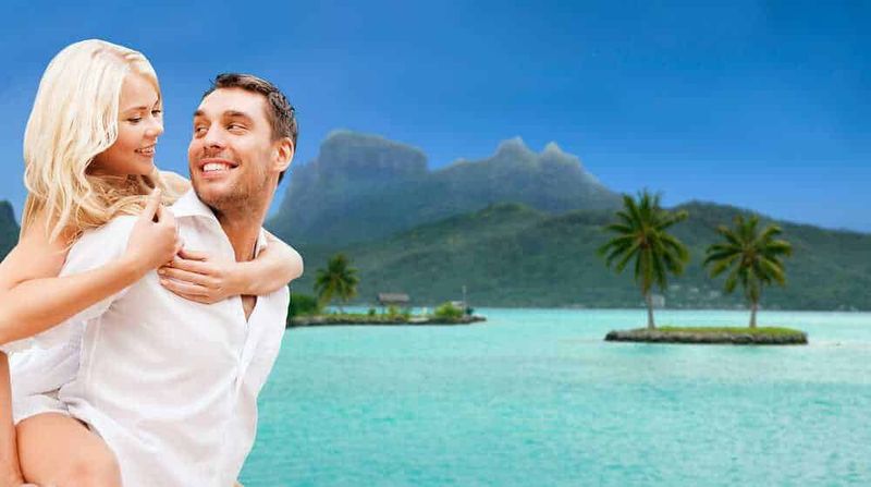 Destinazioni incantevoli per viaggi indimenticabili 8 Coppia felice in vacanza tropicale con mare cristallino, palme e montagne sullo sfondo, atmosfere romantiche e relax, viaggio alle isole paradisiache, guida turistica, destinazioni di mare.