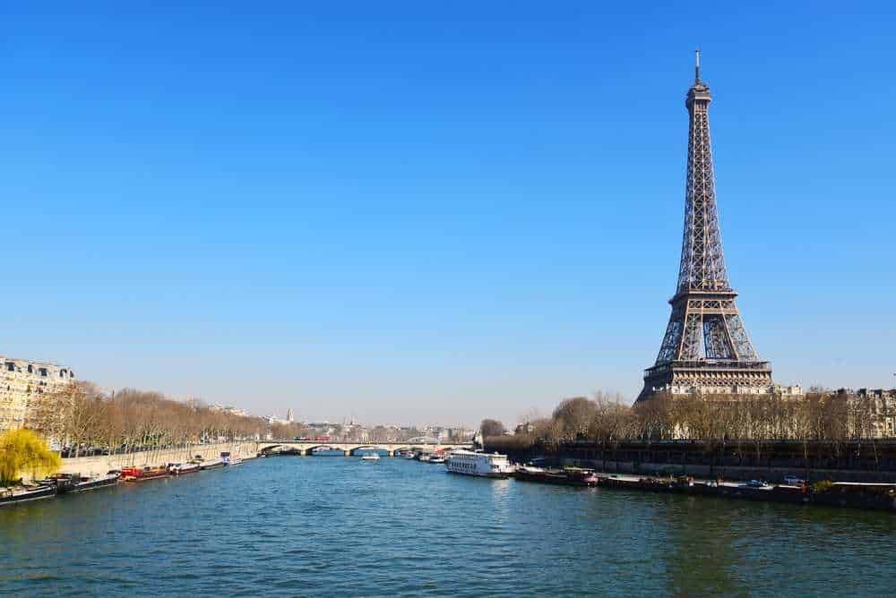 Eiffel Tower vista sulla Senna a Parigi in una giornata soleggiata. Iconico monumento francese tra i principali punti turistici e simbolo di romanticismo, con il fiume e le barche sullo sfondo.