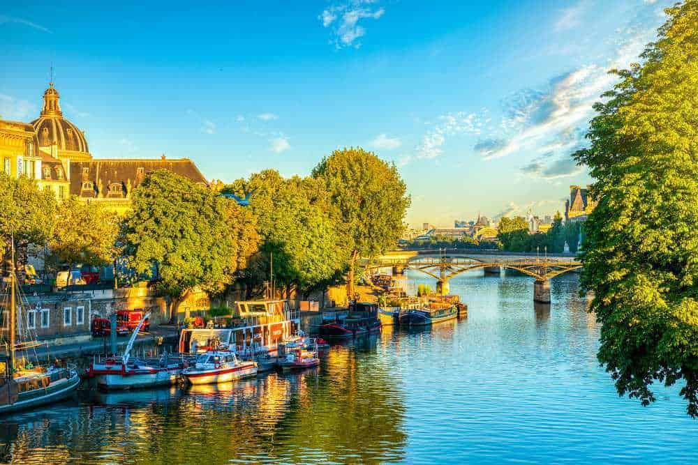 Vita fluviale a Parigi con barche e ponti sotto un cielo sereno e soleggiato. Un’immagine tranquilla e pittoresca del fiume Senna, ideale per articoli su viaggi, turismo e luoghi iconici.