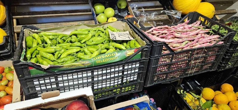 Frutta e verdura ad Agosto, scelta e conservazione 2 Frutta e verdura di agosto: Fresh green peppers in crates at a farmers market for healthy cooking ingredients, showcasing fresh produce selection.